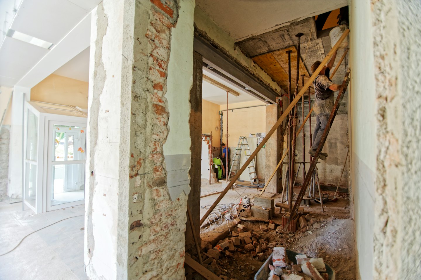 Operai edili ristrutturano un edificio con muri di mattoni a vista.